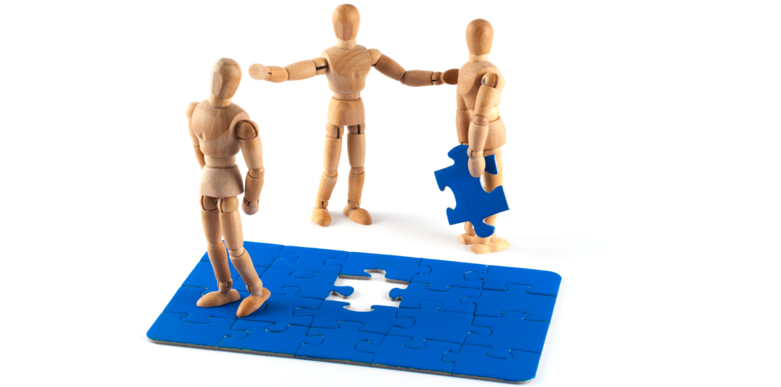 Jigsaw with one piece being held by a wooden doll