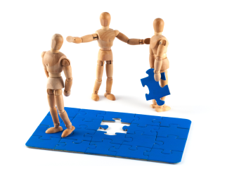 Jigsaw with one piece being held by a wooden doll