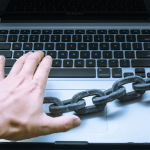 Person using laptop with a large chain across