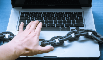 Person using laptop with a large chain across
